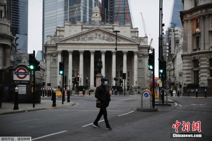 当地时间1月5日,英国采取了第三次严格性封锁措施,伦敦街头行人稀少。图为一名行人穿过英国皇家交易所前的街道。 点击进入下一页